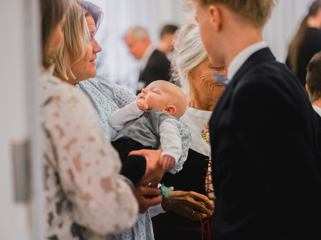 Personer på en dopfest. Babyn är i mittpunkten.