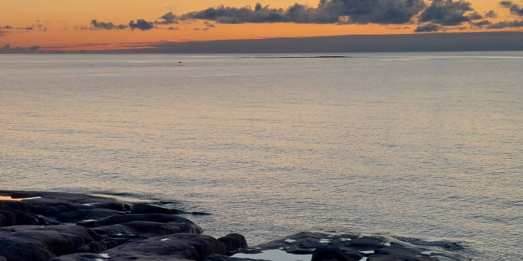 Meri ja kalliot auringonlaskussa.