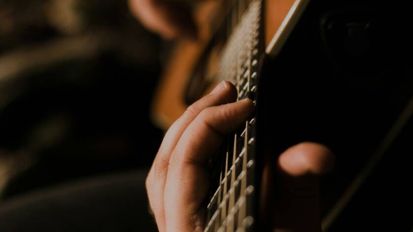 händer som spelar på gitarr