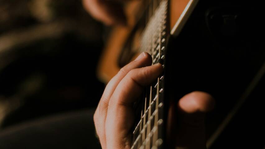 händer som spelar på gitarr