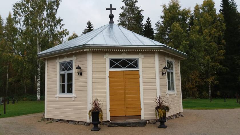 Esse gravkapell är en liten sexkantigbyggnad med fasad i beige och en mörkgul dubbeldörr.