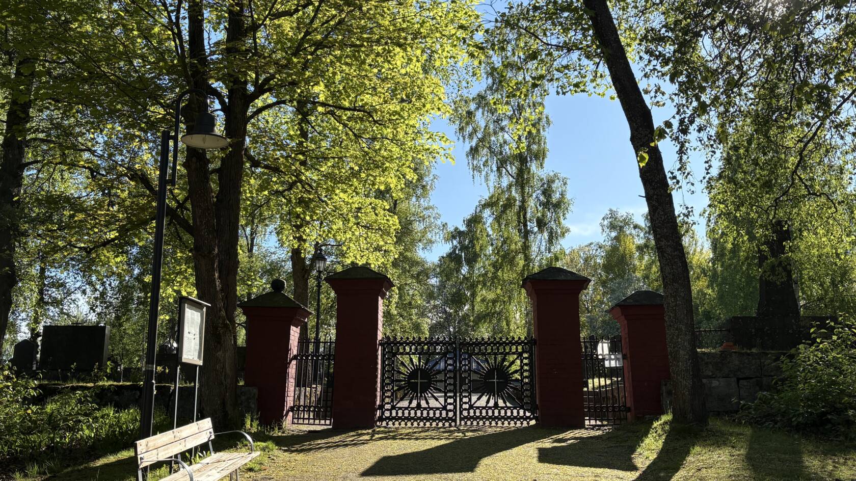 Röda stolpar med svarta gjutgärnsgrindar till Jakobstads gamla begravningsplats.