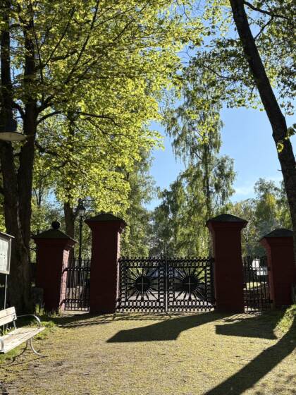 Röda stolpar med svarta gjutgärnsgrindar till Jakobstads gamla begravningsplats.