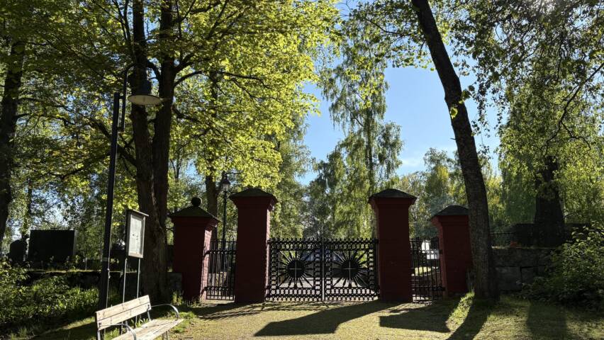 Röda stolpar med svarta gjutgärnsgrindar till Jakobstads gamla begravningsplats.