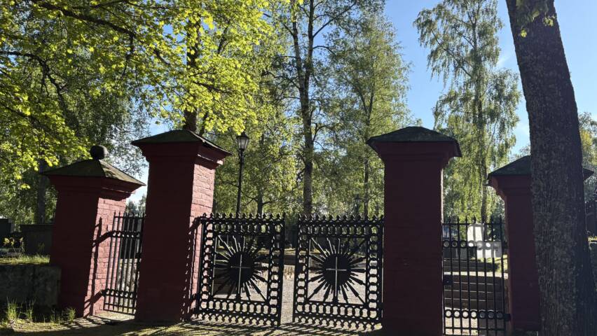Punaiset pylväät ja mustat valurautaportit Pietarsaaren vanhalle hautausmaalle.